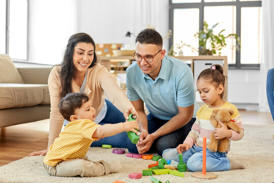 family and people concept - happy mother, father, little daughter and baby son playing with wooden toys at home - Powered by Adobe