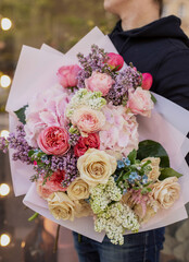 Colorful flowers assorted bouquet in bright paper. Holiday celebration concept. Bouquet of beautiful flowers in hands. Colorful flowers bouquet wrapped in paper