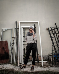 Beautiful Asian Muslim woman posing and stylish with the background of junk and scrap metal.