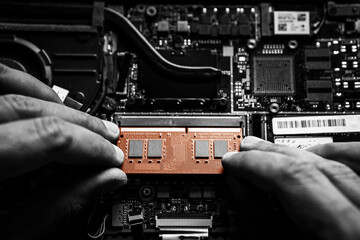 Close-up on the orange RAM memory that the hands of the service technician insert into the slot on...