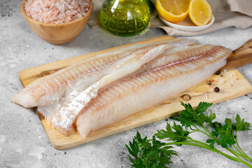 Cod fillet. Raw cod fillet on a chopping Board on a light gray kitchen table. Preparation for salting fish