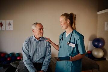 Smiling nurse supporting senior patient after showing reports on digital tablet in hospital