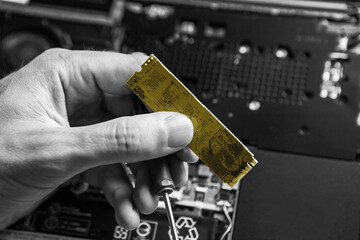 The service technician holds a new yellow ssd drive in his hands, which he wants to put in the...
