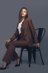 Fashion minimalist portrait of brunette female model on grey background. stylish clothing with scottish color, casual suit with women akcent  white silk shirt