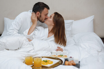 Obraz na płótnie Canvas Breakfast and kissing in white bed