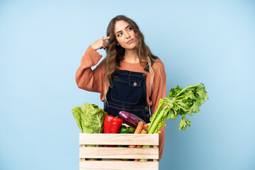 Farmer with freshly picked vegetables in a box making the gesture of madness putting finger on the...