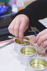A Chandler or candle maker adds a wick to scented hand made candles
