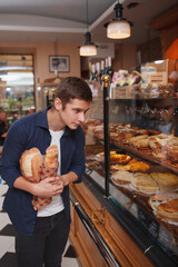 Vertical shot of a male customer choosing desserts from the display at the bakery