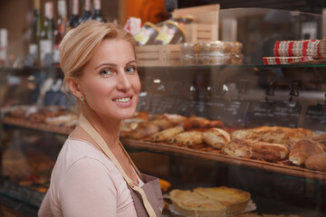 Charming beautiful mature woman smiling while working at her bakery store