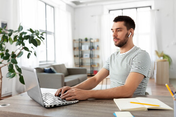 technology, remote job and business concept - man with laptop computer and earphones working at home office