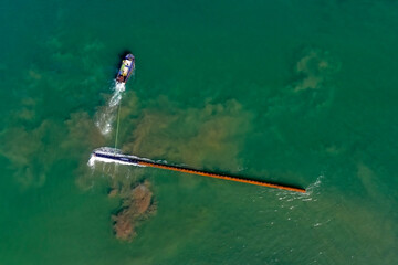 Aerial view of the boat during carry a long pile (stake) on the water to build pier (series-1).