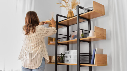 home improvement, decoration and people concept - woman placing aroma reed diffuser to shelf - obrazy, fototapety, plakaty