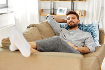people and leisure concept - young man sleeping on sofa at home