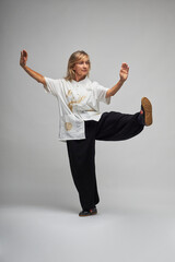 Mature blonde woman practicing Chi kung and Tai Chi on a white background. She wears a traditional white chinese Tai Chi jacket, black trousers and black shoes with ying yang symbol