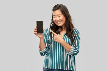 Fototapeta premium people and technology concept - happy asian young woman with smartphone over grey background