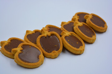 Fresh delicious crunchy shortbread cookies with nutty, chocolate filling inside. Apple-shaped cookies with brown filling located on a white matte background.