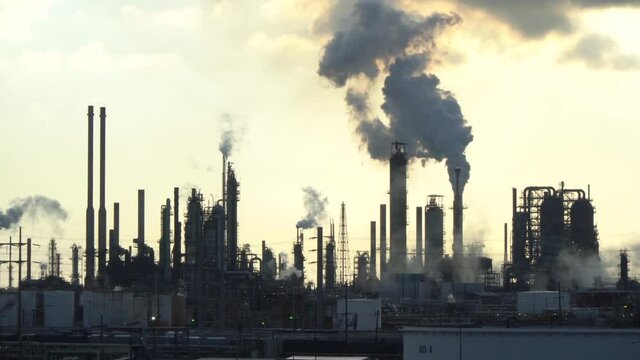 Smoking chimneys of an oil refinery at sunrise.