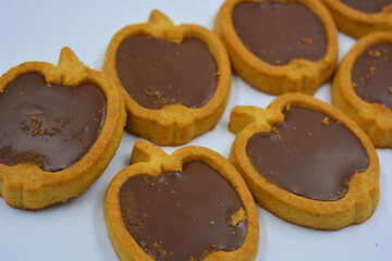 Fresh delicious crunchy shortbread cookies with nutty, chocolate filling inside. Apple-shaped cookies with brown filling located on a white matte background.