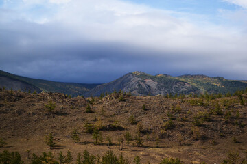 Baikal grassy mountains covered with green trees. Autumn landscape. Cloudy sky