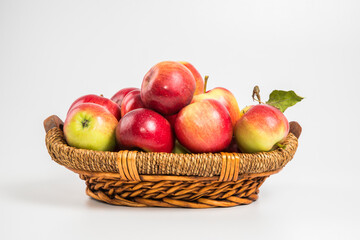 Bright multi-colored fresh apples in a wicker basket on a white background. Selective focus.