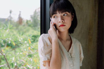 Fototapeta premium Beautiful asian thai woman short dark hair using smartphone at countryside hotel room.