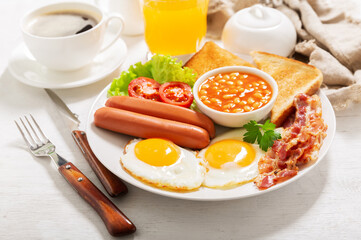 breakfast with plate of fried eggs, bacon, beans, sausages, toasts and tomatoes