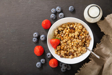 breakfast with bowl of granola, fresh berries and bottle of milk, top view