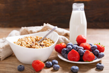 breakfast with bowl of granola, fresh berries and bottle of milk