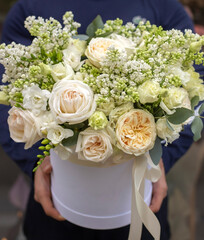 Bouquet in box. Gift box with beautiful flower. Woman holding big beautiful blossoming box bouquet of fresh roses, lilac, freesia, eustoma and others.
