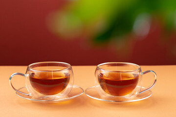 Two glass cups of black tea on beige table