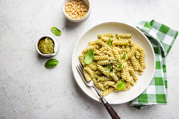 Italian Fussili pasta with basil pesto and fresh basil on white stone background. Top view.