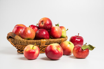Bright multi-colored fresh apples in a wicker basket on a white background. Selective focus.