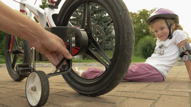 Kids bike. Father removes training wheels from the child's bike. Father teaches his daughter to ride a bicycle without training wheels.