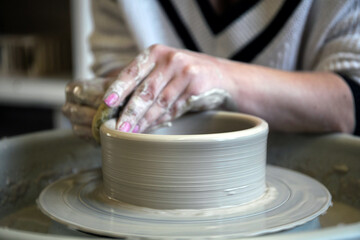 Girl Potter works with clay on a Potter's wheel.
