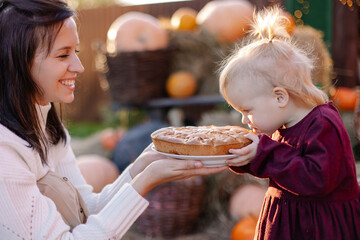 small happy family celebrating Thanksgiving. Mom feeds her daughter sweet pie. funny toddler eating with a good appetite. Fun photo curiosity. Harvesting eco nature gifts autumn. countryside lifestyle