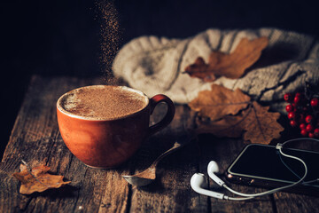 Cozy background with cup of coffee, headphones and Autumn leaves on wooden background