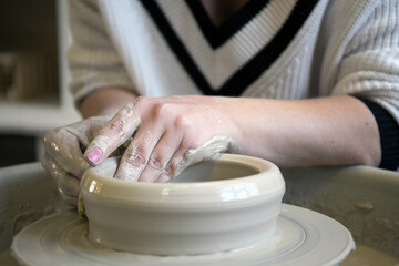  Girl Potter works with clay on a Potter's wheel.
