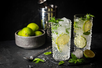 Glass of iced lemonade with lime and mint, cold summer drink on dark background
