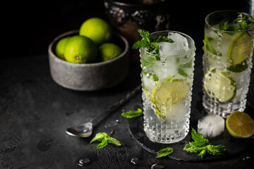 Glass of iced lemonade with lime and mint, cold summer drink on dark background