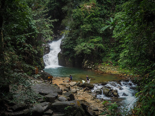waterfall falling into blue pool and flowing in green forest.