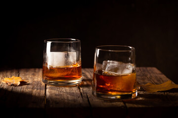 Glass of scotch whiskey and ice on wooden background