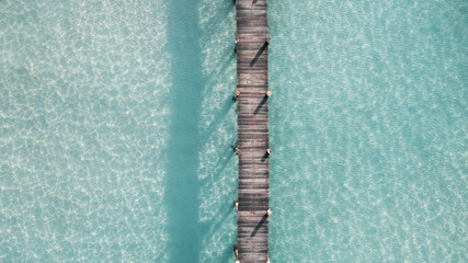 aerial view of wooden bridge over the transparent sea water near beach. jetty on turquoise sea in...
