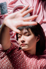 Beautiful asian thai woman short dark hair over pink background, reaching hands at camera.