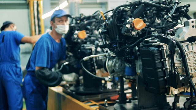 Car engines are getting assembled by factory workers. Automobile factory, car production, auto production line.