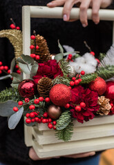 Christmas bouquet. Red flower of carnation, cone and cotton with Christmas tree branches. New year bouquet flowers and fir branches in a basket. Christmas wreath