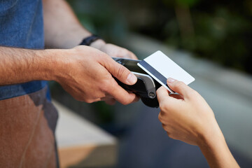 Close-up of waiter holding payment terminal while woman using her credit card