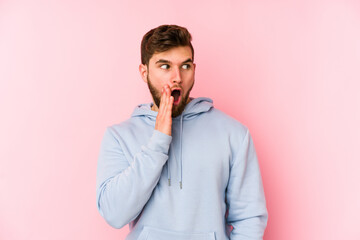 Fototapeta premium Young caucasian man isolated on pink background is saying a secret hot braking news and looking aside