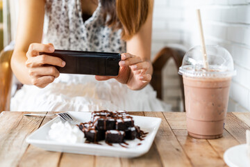 Young woman taking photo of food with smart phone in restaurant while traveling