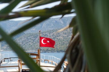 Turkish flag fluttering on the upper deck of a small pleasure boat with blurred frame foreground