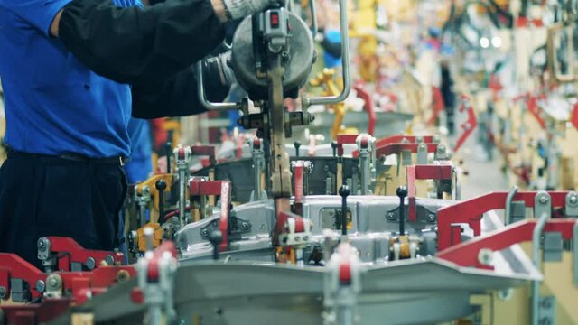 Mechanic is doing spot welding of a car element. Automobile factory, car production, auto production line.